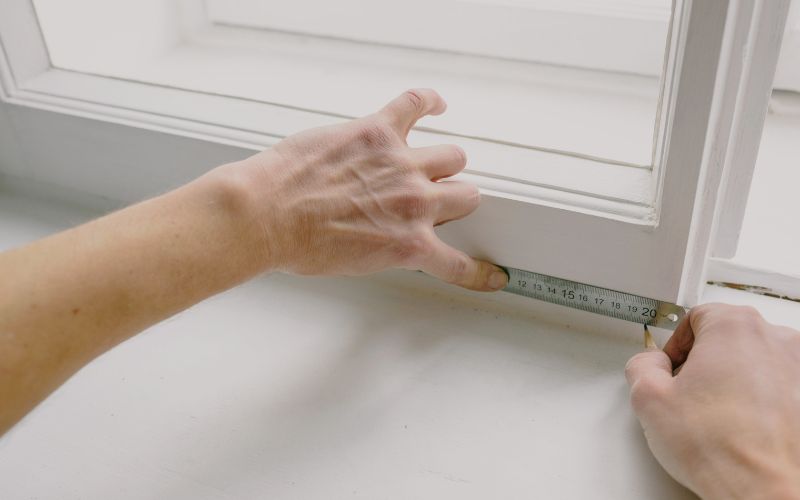 Person taking measurements of a window white frames